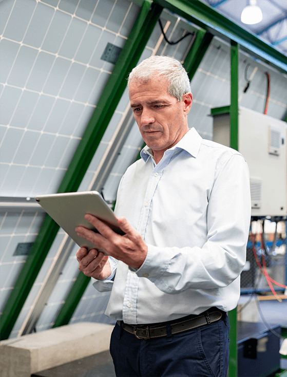 Man standing and looking at a tablet.